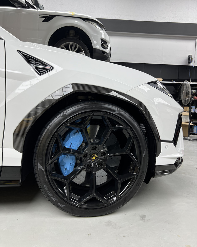 Blue brake caliper behind a black alloy wheel