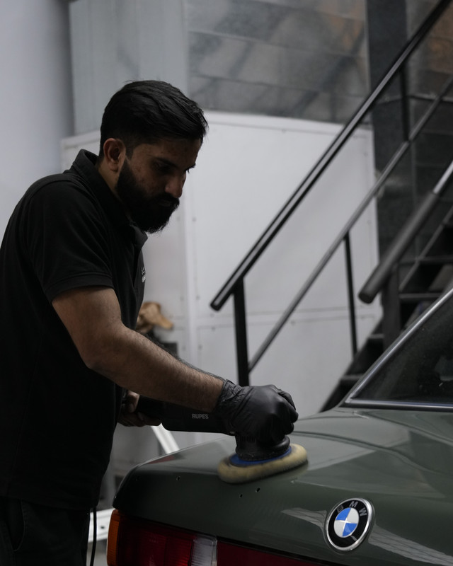 Technician machine-polishing a classic BMW