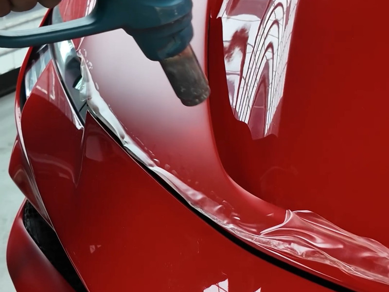 Paint protection film being heat-shrunk on a red Ferrari