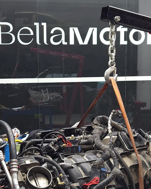 Engine lifted on the crane in front of the Bella Motor workshop