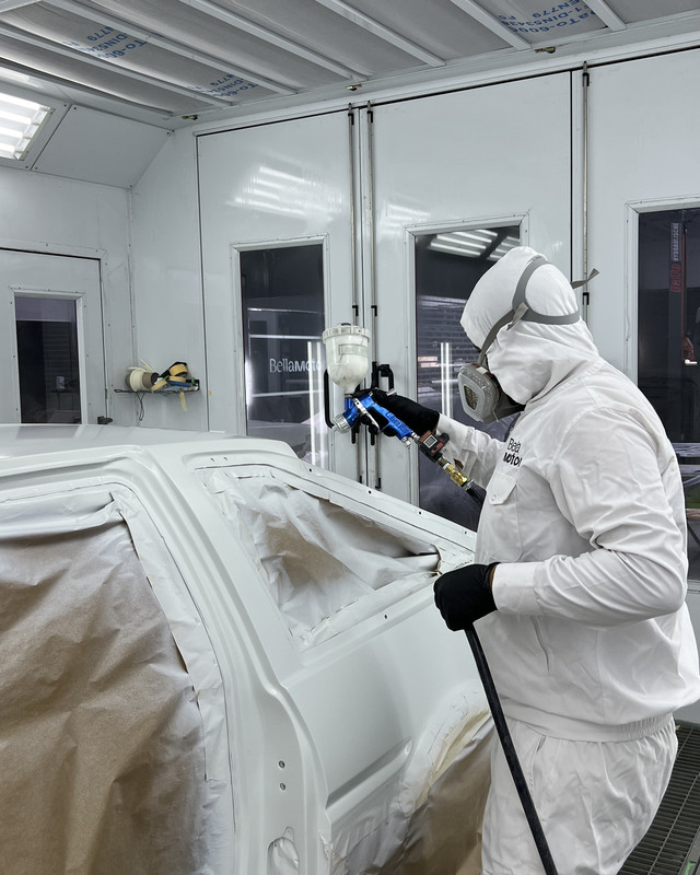 Side of a car being painted in the booth