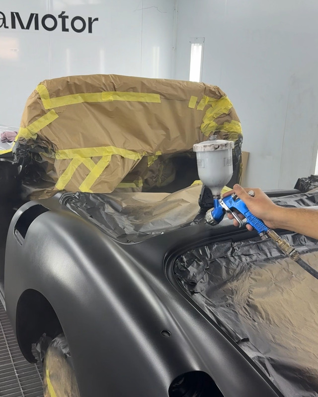 Black car being sprayed in the paint booth