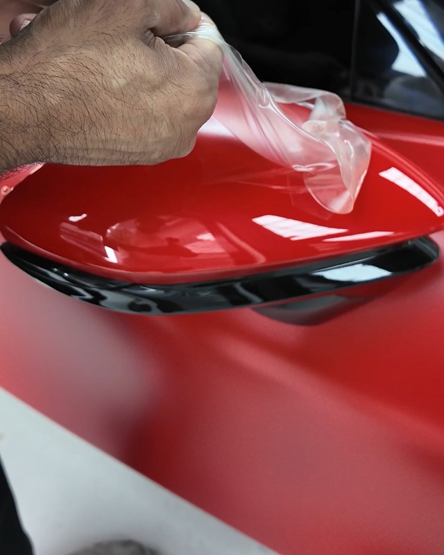 Clear PPF being stretched over a red panel