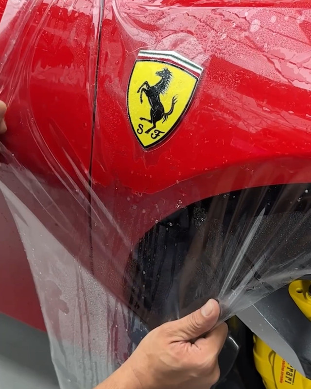 Clear paint protection film fitted by hand on a red Ferrari