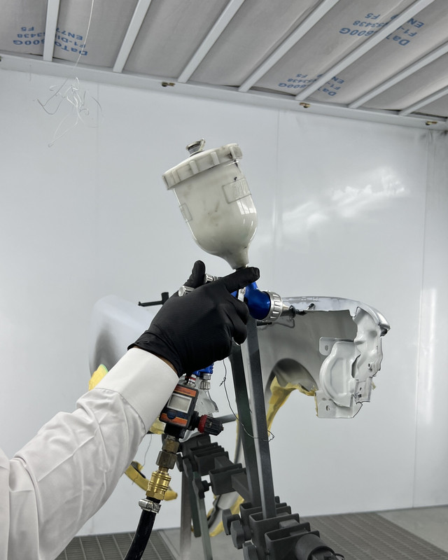 Spray gun applying paint to a panel
