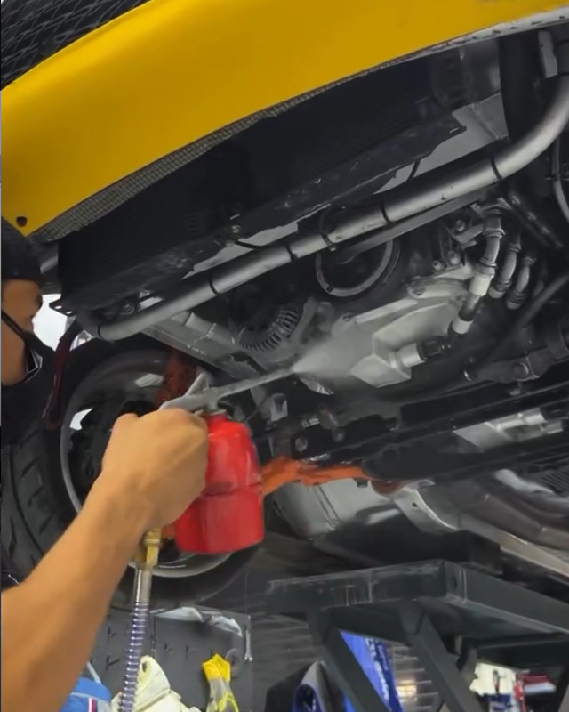 Technician working on the front axle and steering from under the car